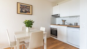 Una cocina moderna con armarios blancos, encimera de madera y un comedor con mesa y sillas blancas.
