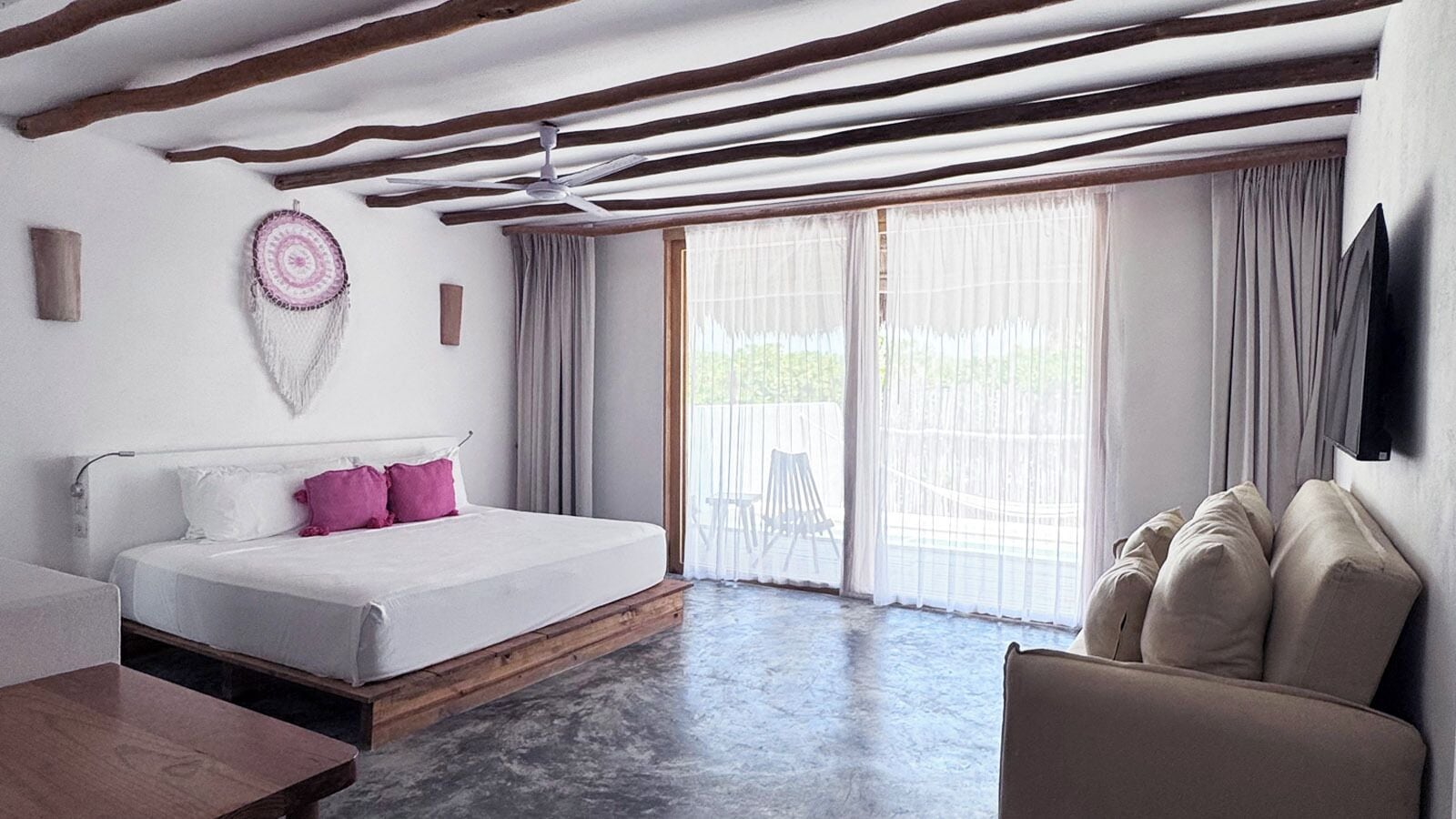 A bedroom with a bed, a chair, a ceiling fan, and a large window with curtains.