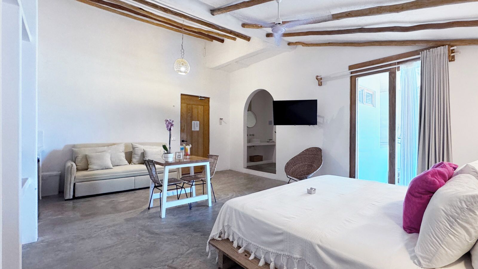 Un dormitorio con cama, sofá, mesa de comedor y televisor.