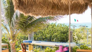 A beachside area with a thatched roof, a kayak, and a welcome sign.