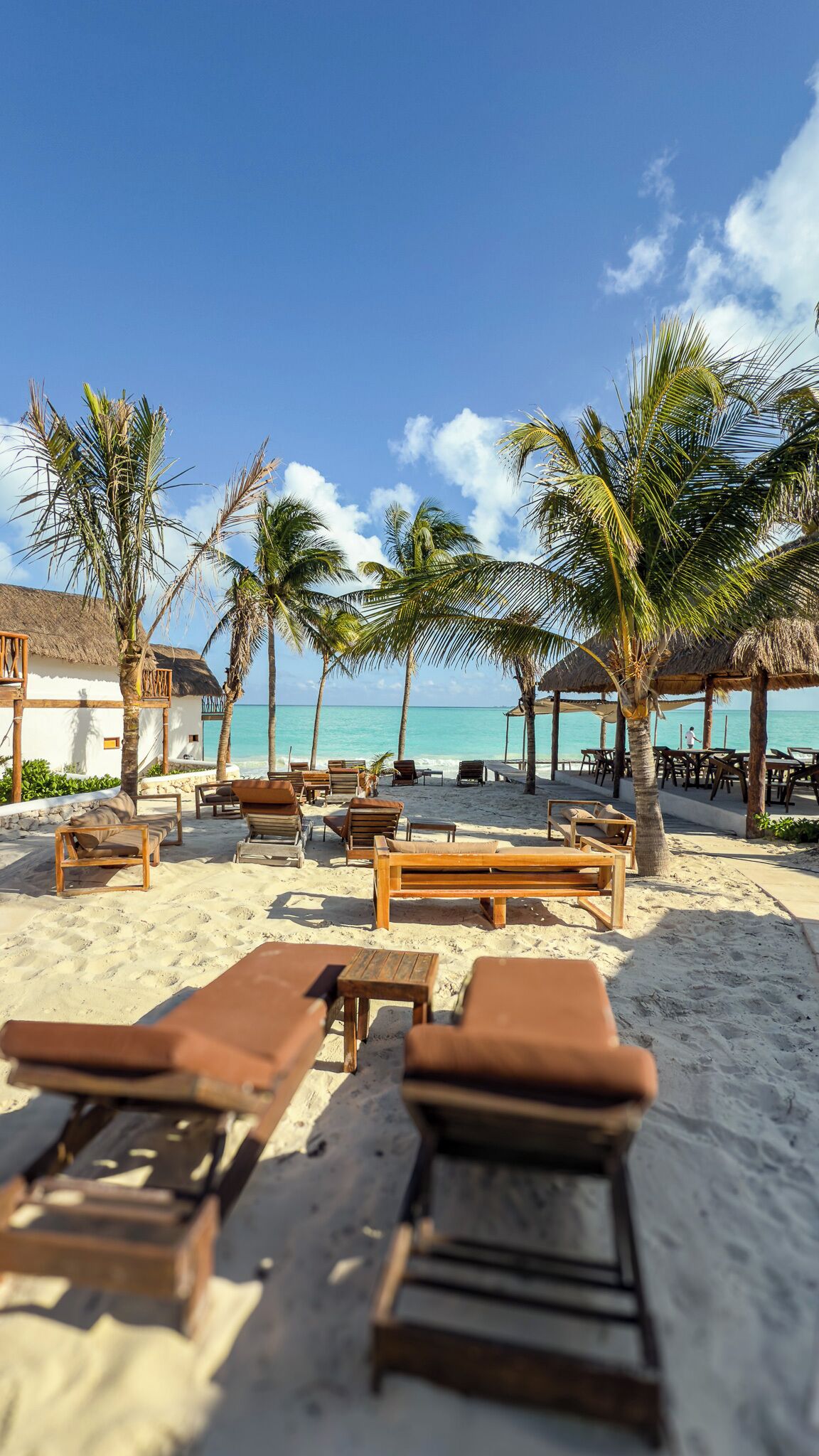 A beachside resort with wooden lounge chairs and thatched-roof structures.