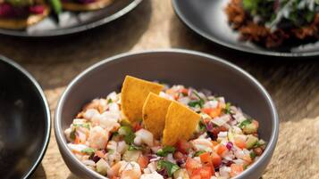 Una mesa con varios platos, incluyendo un bol de ceviche y totopos.