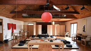 Une pièce spacieuse dotée d’un plancher en bois, de tatamis, d’une table centrale et d’une lanterne rouge suspendue.