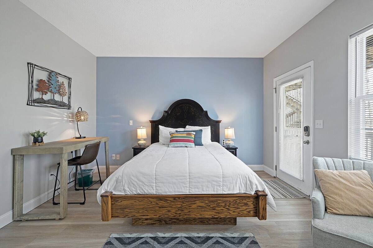 A bedroom with a bed, bedside tables, a desk, and a chair.