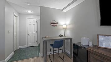 Una habitación pequeña y bien iluminada con un escritorio, una silla y un cartel de bienvenida.