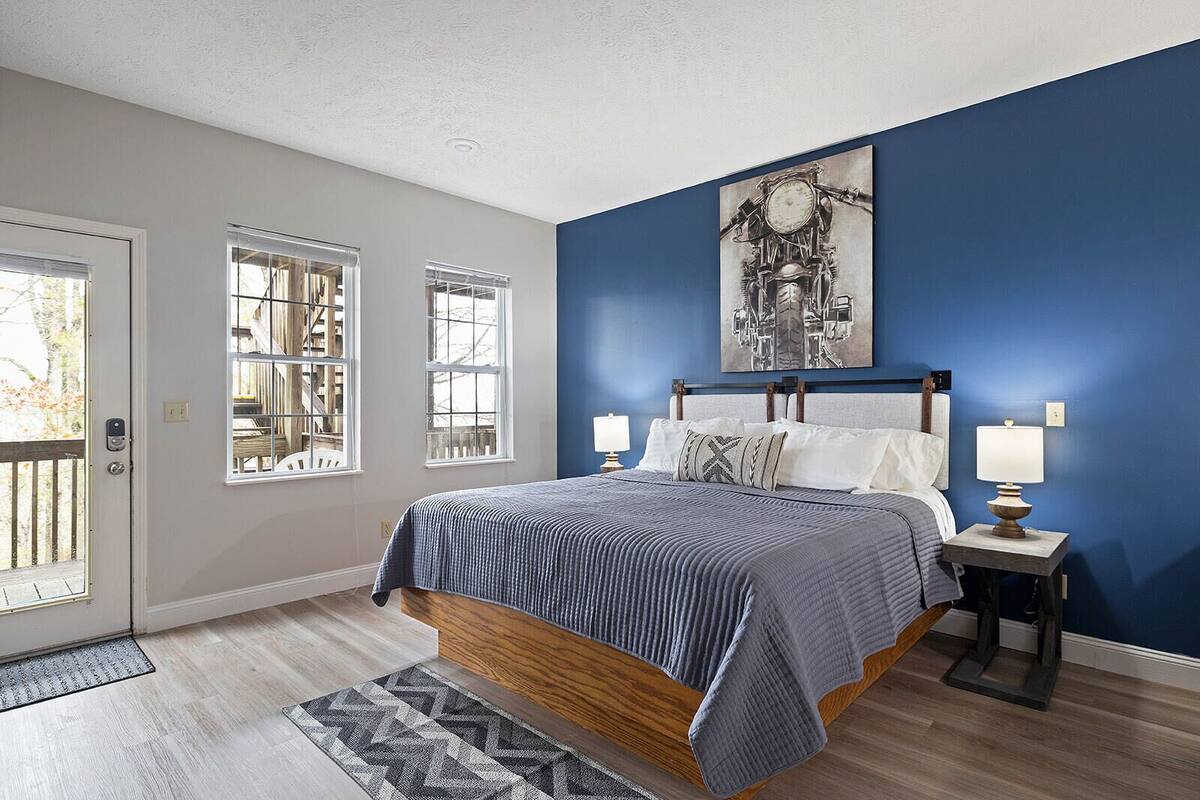 A bedroom with a bed, two bedside tables, a window, and a door.