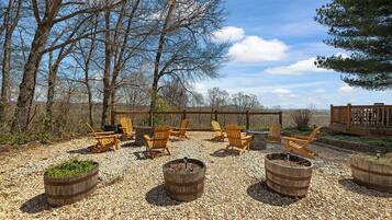 An outdoor seating area with Adirondack chairs, a fire pit, and a wooden deck.