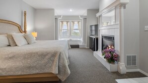 A bedroom with a large bed, a fireplace, a TV, and a window with curtains. - The Bradford (Branson)