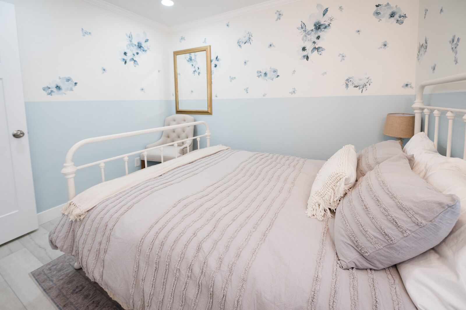 A bedroom with a bed, a chair, and a mirror on the wall.
