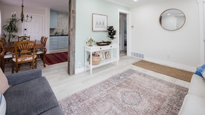 Un salon comprenant un canapé, une table basse, un tapis et une console sur laquelle sont disposés des objets décoratifs.