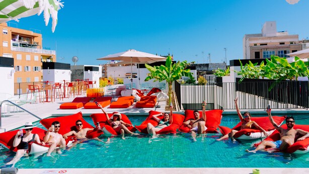 A swimming pool area with red lounge chairs and umbrellas. - The Boc Hostels City - Youth Hostel (Palma de Mallorca)