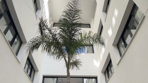 A modern building with a central courtyard featuring a tall palm tree. - The Boc Hostels City - Youth Hostel (Palma de Mallorca)