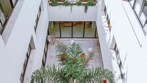 A multi-level atrium with balconies, potted plants, and a central seating area. - The Boc Hostels City - Youth Hostel (Palma de Mallorca)