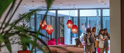 A modern interior with a glass wall, red pendant lights, and a seating area with a table and chairs.