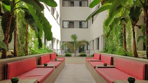 A courtyard with red benches and a central plant. - The Boc Hostels City - Youth Hostel (Palma de Mallorca)