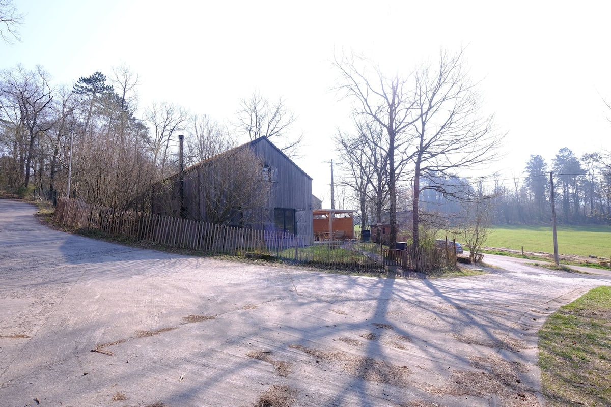 A rural property with a large barn, a fenced yard, and a gravel driveway.