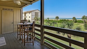 A covered outdoor area with a table and chairs, a ceiling fan, and a view of the beach and ocean. - Ocean Views with Easy access to pools and beach (Tybee Island)