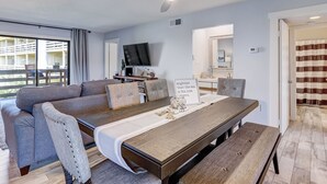 A modern living room with a sofa, a dining table, and a ceiling fan. - Ocean Views with Easy access to pools and beach (Tybee Island)