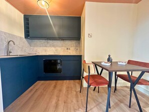 A compact kitchen with a built-in oven, a sink, and a dining area with a table and chairs.