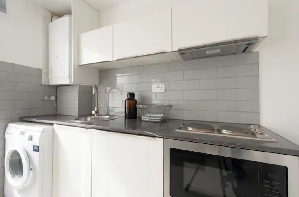 Una cocina compacta con lavadora, microondas y cocina a gas.