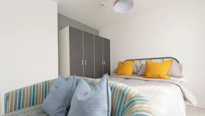 Une chambre à coucher avec un lit, un canapé à rayures et une armoire.