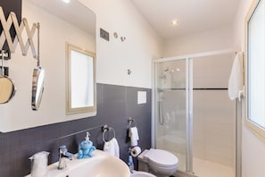 Ein modernes Badezimmer mit einem großen Spiegel, einem Waschbecken, einer Toilette und einer Duschkabine.