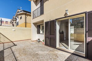 A residential building with a tiled patio, a sliding glass door, and a small balcony.