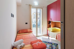 Ein Schlafzimmer mit Bett, Fenster, Tür und einem kleinen Tisch mit Lampe.