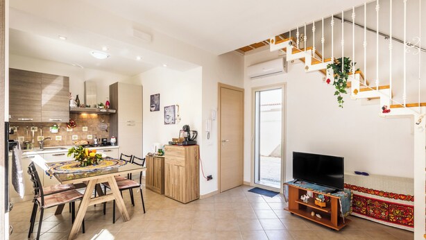 Una cocina moderna con comedor, una escalera y un televisor en la sala de estar.