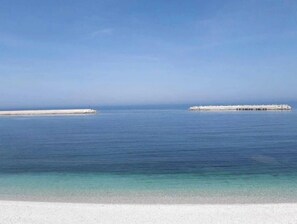Une plage avec une eau d’un bleu limpide et un rivage sablonneux.