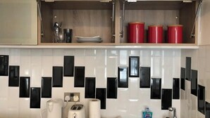 Una cucina con piastrelle a parete, un tostapane, un bollitore e un lavandino.