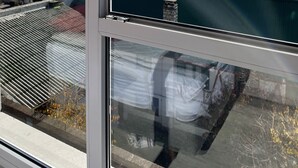 Uitzicht door een raam op een gebouw met een berg op de achtergrond en een meer.