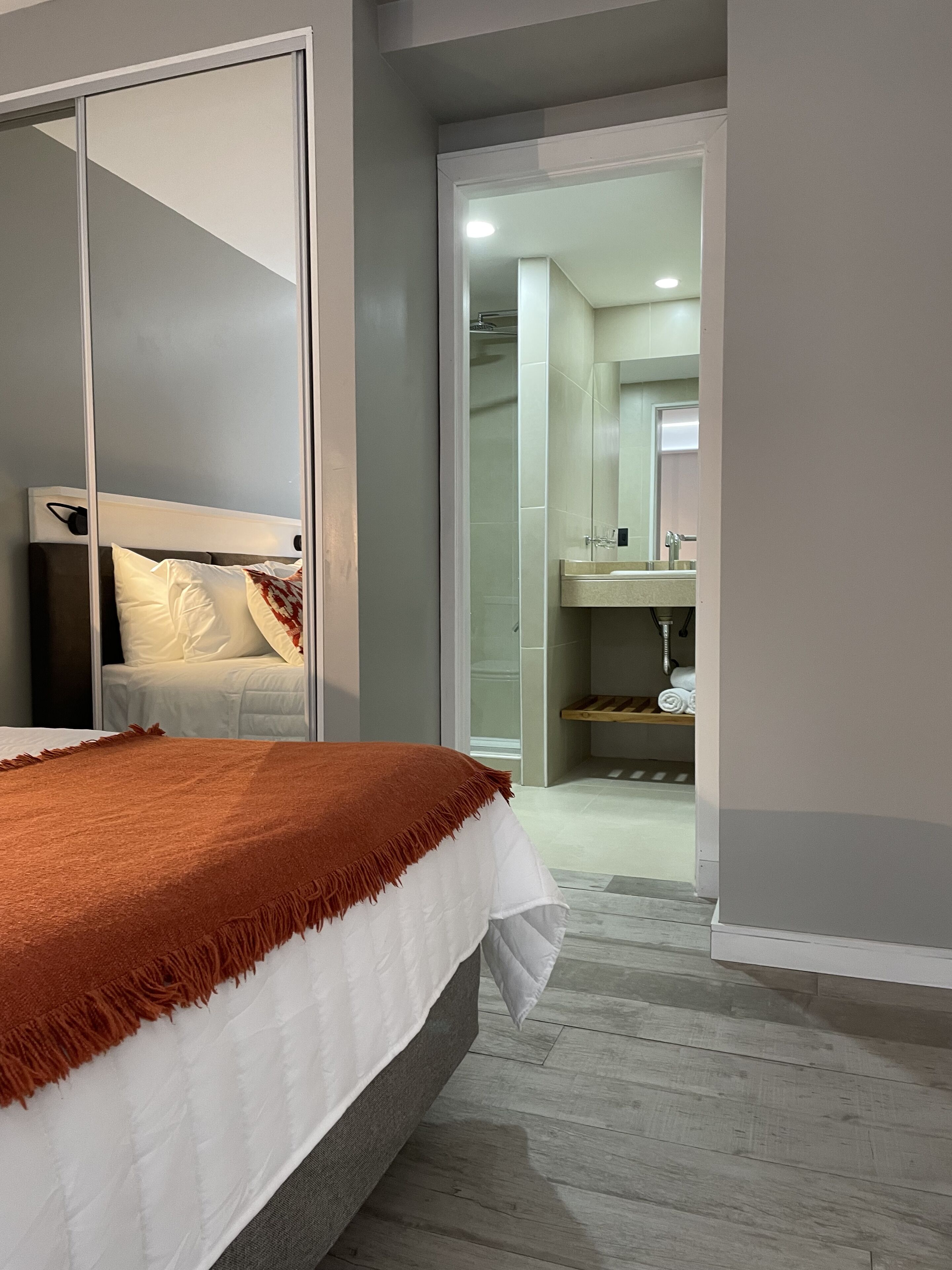Une chambre à coucher avec un lit, une armoire et une salle de bain visible à travers une porte ouverte.