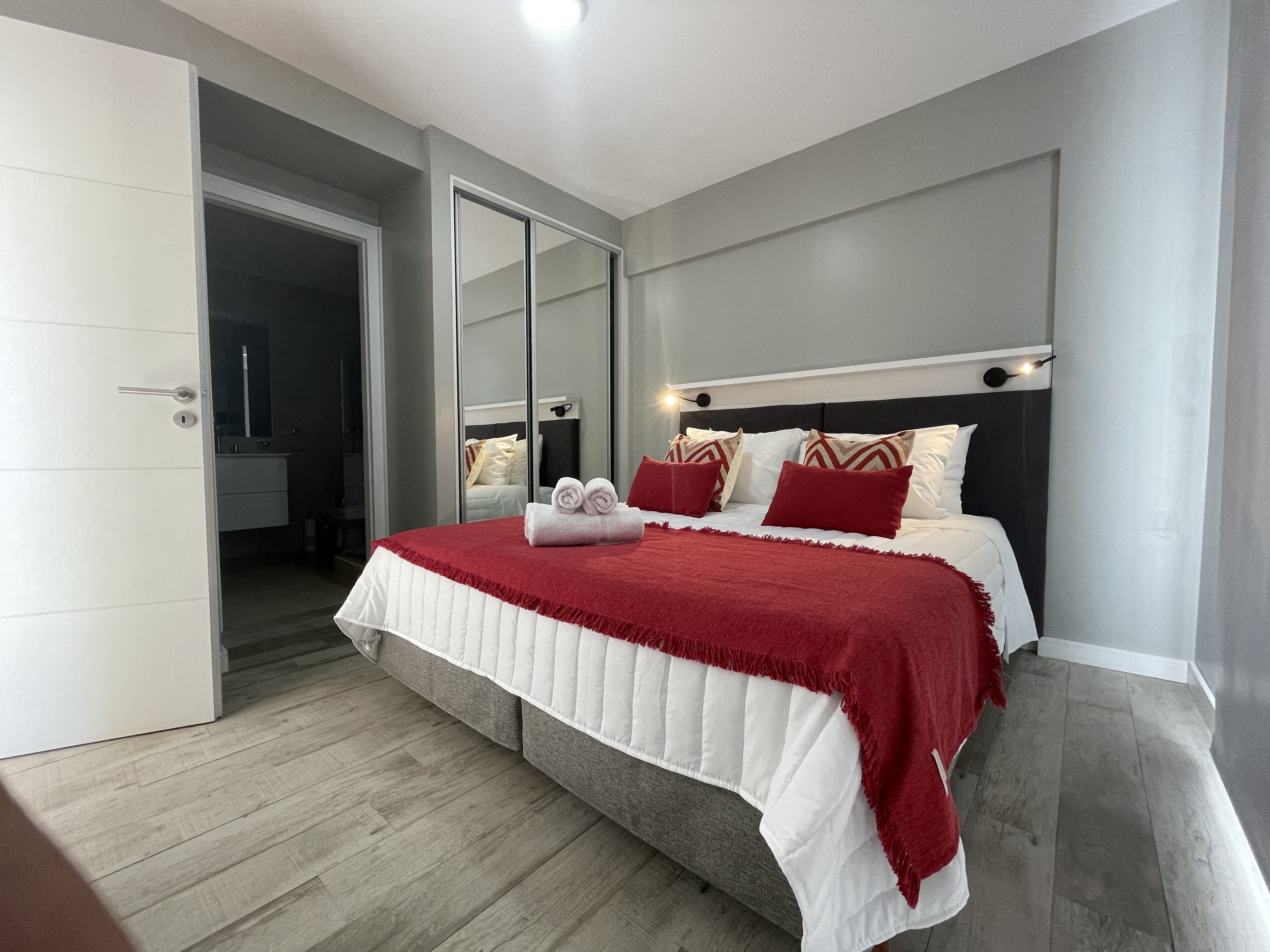 A bedroom with a bed, a mirror, and a door.