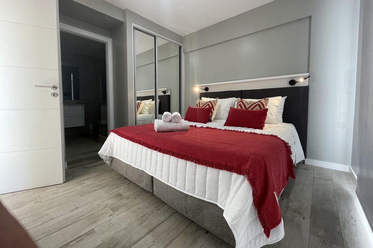 Une chambre à coucher avec un lit, un miroir et une porte.