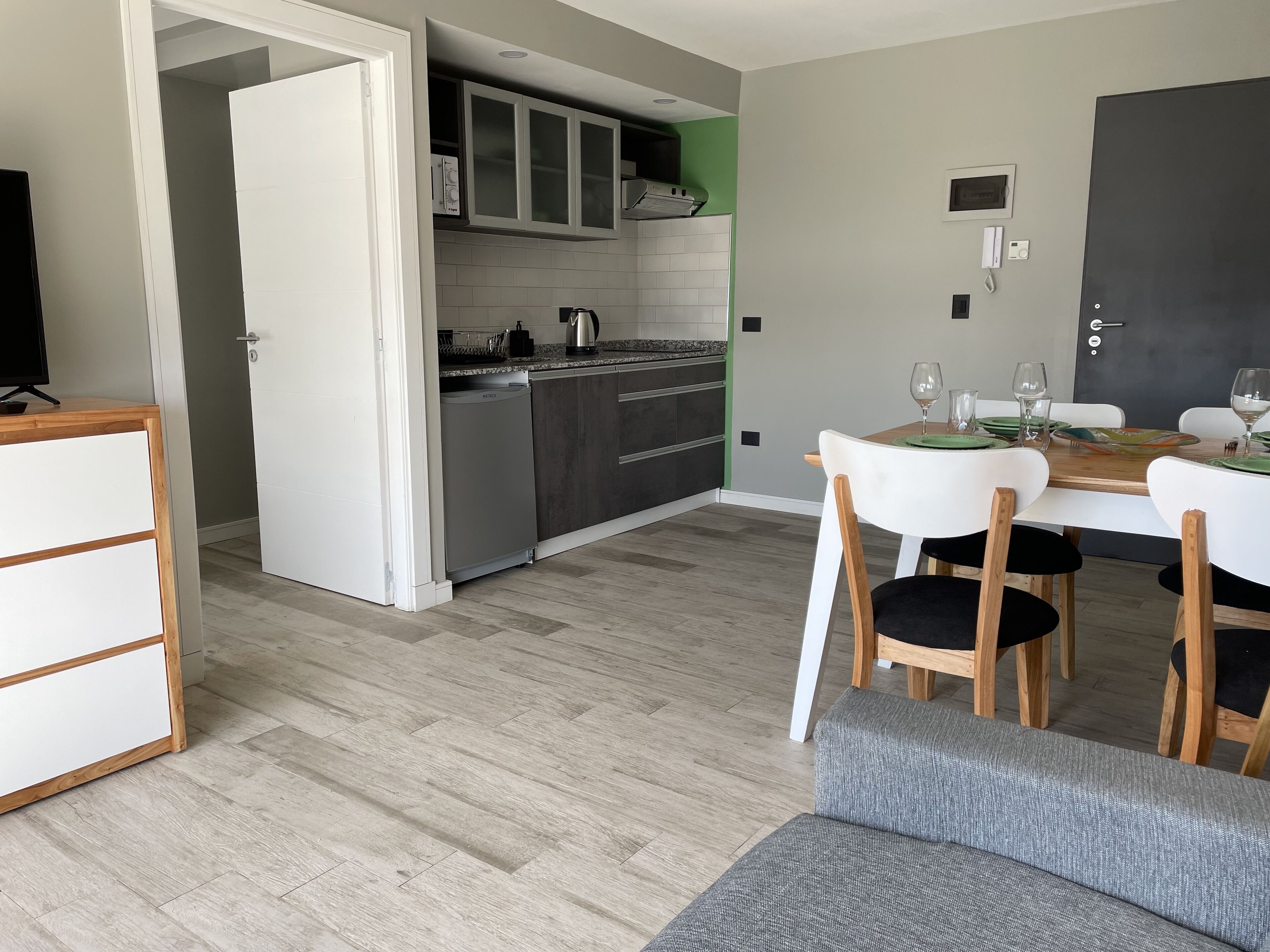 A modern kitchen with white cabinets, a built-in oven, and a dining area with a table set for two.