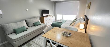 A compact living space with a sofa, a dining table, and a bed.