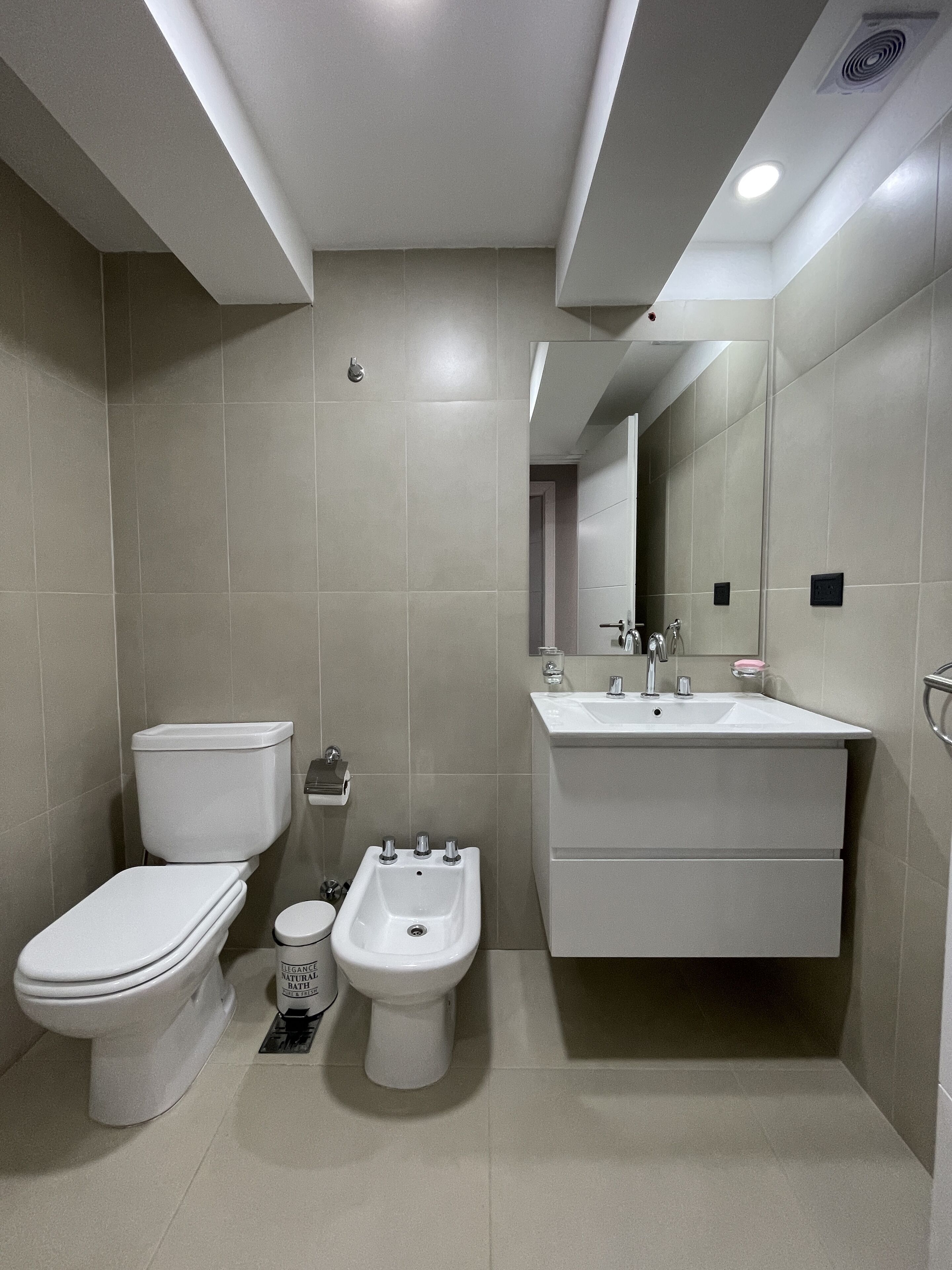 A modern bathroom with a toilet, bidet, and sink.