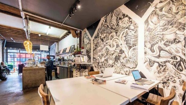 Zona pranzo con tavolo, sedie e parete decorata con un'opera d'arte in bianco e nero.