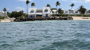 A beachfront property with a large rock barrier, white buildings, and palm trees.