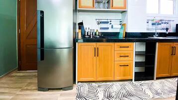 Una cocina con refrigerador de acero inoxidable, armarios de madera y encimera negra.