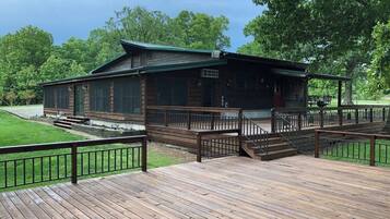 A wooden cabin with a deck, surrounded by trees.