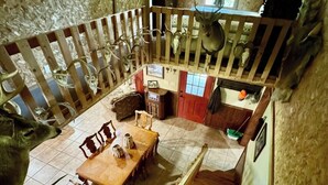 Ein rustikales Interieur mit einer Holztreppe, einem Essbereich mit Tisch und Stühlen sowie einem Schlafbereich mit Holzbalkon.