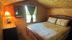 Ein Schlafzimmer mit einem hölzernen Bett, einem Nachttisch, einer Lampe und einem Fenster mit Vorhängen.