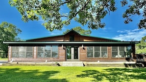 A two-story wooden building with large windows and a green roof.