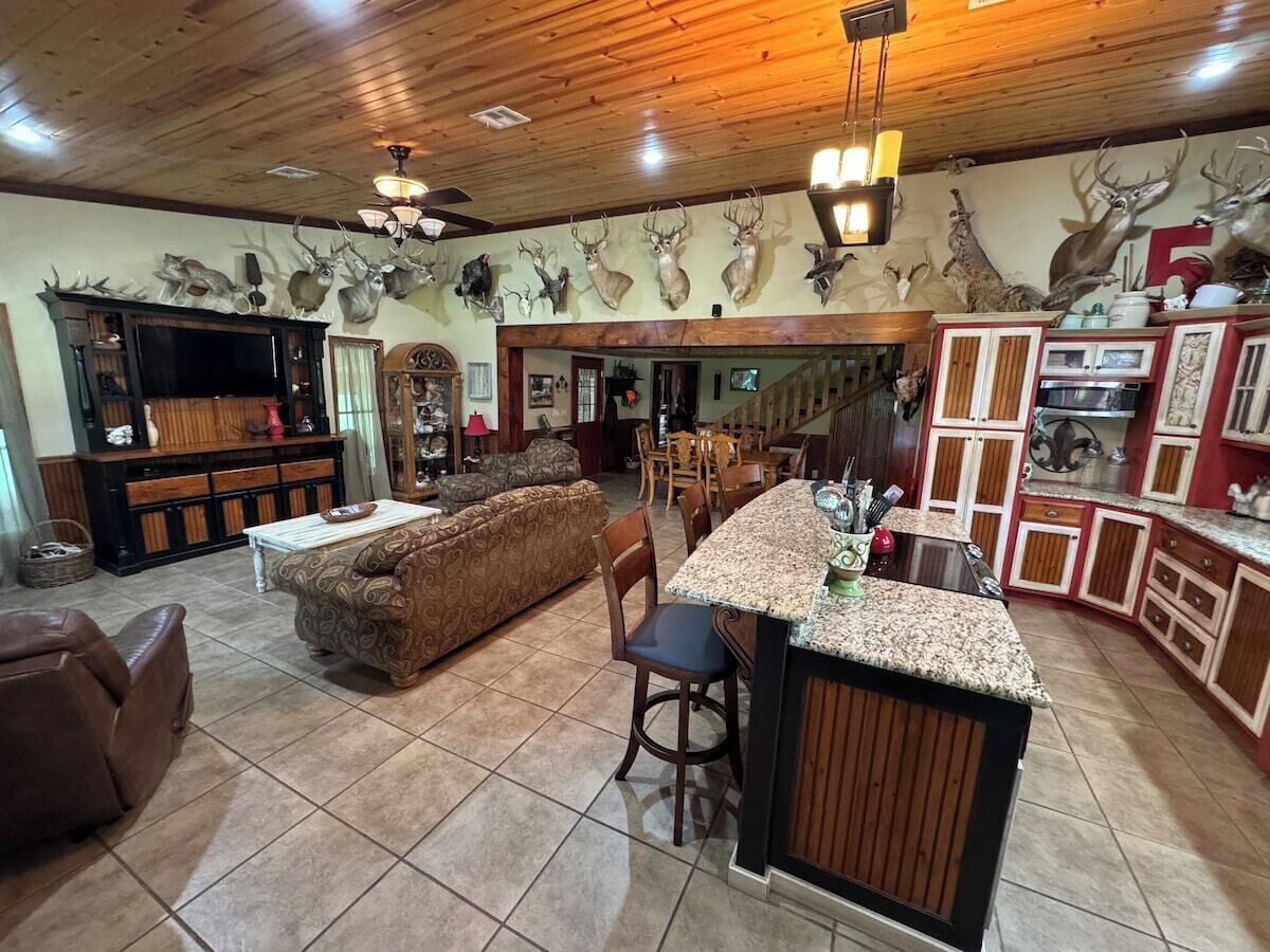 A spacious living area with a large sofa, a bar area with a granite countertop, and a dining area with wooden furniture.