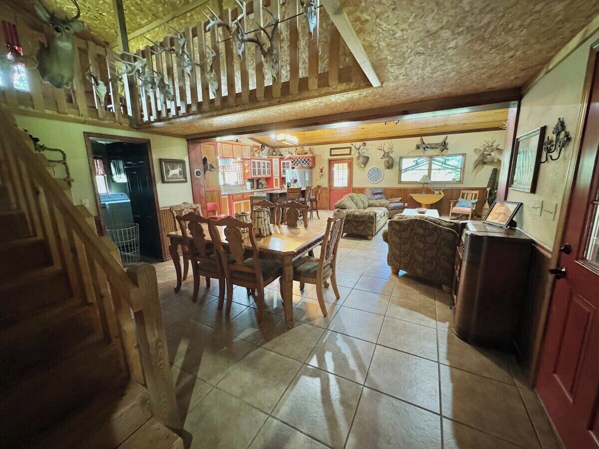 Une salle à manger spacieuse avec un plafond haut et un escalier menant à un niveau supérieur.