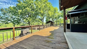 A wooden deck with a railing, overlooking a grassy area and trees.