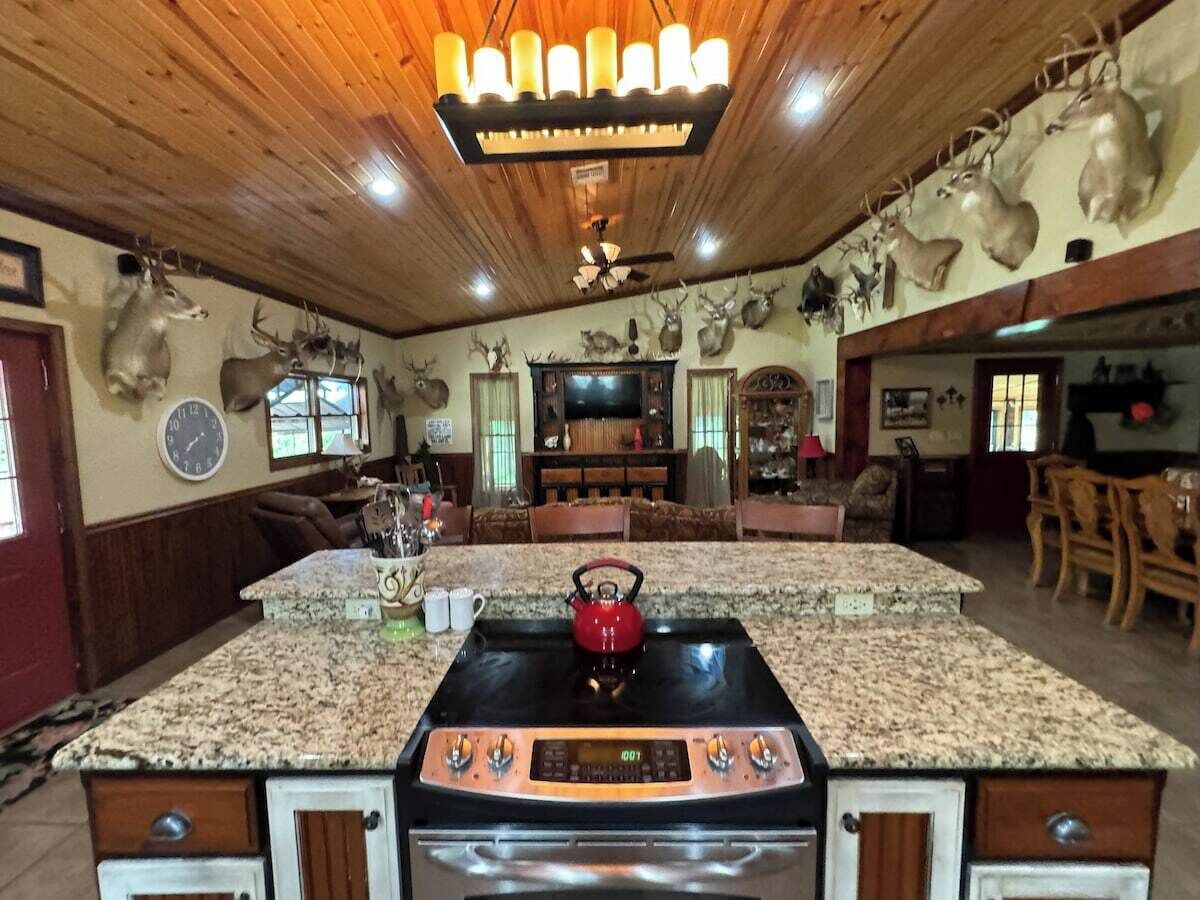 A kitchen with a granite countertop, a red kettle, and a stove.