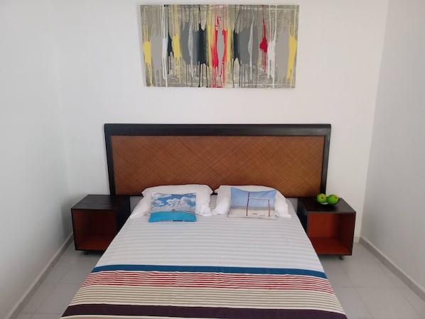 A neatly made bed with striped bedding, two pillows, and a headboard. - Las Palmas Hostal - Hostel (Cancun)